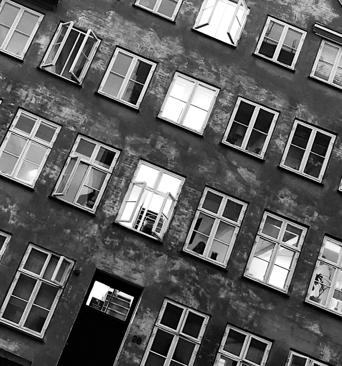 Ett svartvitt fotografi på ett hus med några fönster öppna.